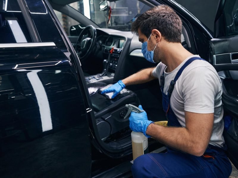 male-wiping-seat-clean-in-black-car-during-detailing.jpg